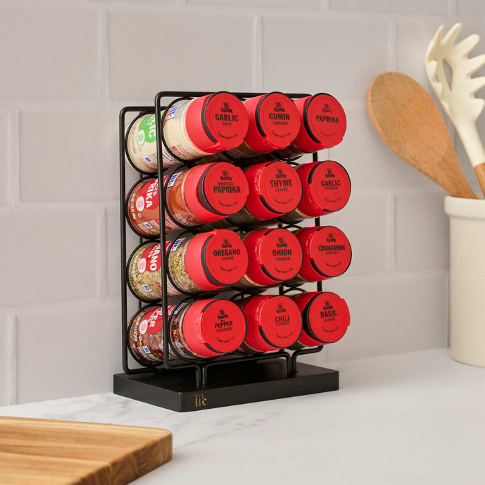 A Kamenstein spice rack filled with spices sits on a kitchen counter.