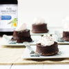 A plate of chocolate lava cakes topped with whipped cream and sprinkled with herbs.