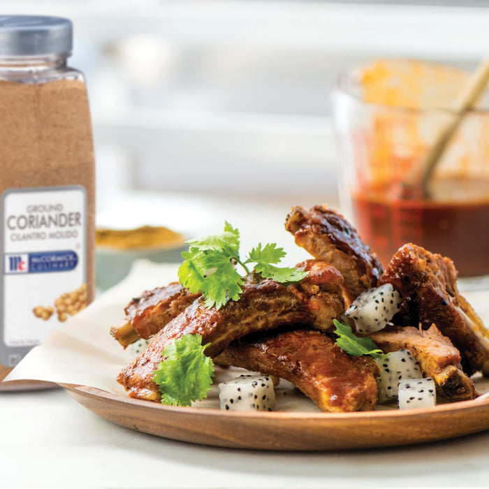 McCormick Ground Coriander spice jar next to a plate of ribs with dragon fruit and cilantro.