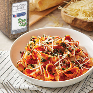 A bowl of pasta with tomato sauce parmesan cheese and marjoram leaves from McCormick Culinary.