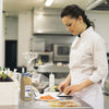 A chef in a white uniform is preparing food in a kitchen using McCormick Culinary Ground Rosemary.