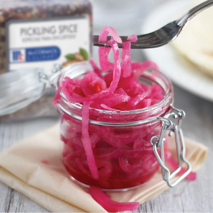 A jar of pickled onions with a fork holding a piece of onion.