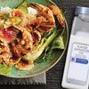 A bowl of shrimp rice and vegetables with a container of McCormick Culinary Flavor Enhancer MSG.