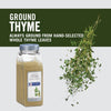 A jar of McCormick Ground Thyme with fresh thyme sprigs falling around it.