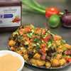A plate of tater tots topped with steak cheese tomatoes and green onions with a side of McCormick Culinary Dark Chili Powder.