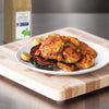 A plate of roasted chicken squash and potatoes sits on a wooden cutting board.