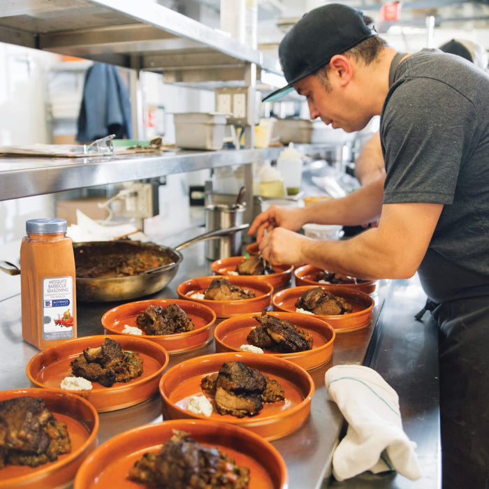 A chef is plating a dish of meat with a side of sauce using McCormick Culinary Mesquite Barbecue Seasoning.