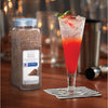 A glass of red cocktail with a basil garnish sits on a black and white napkin next to a McCormick Culinary Black Pepper shaker.