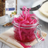 A jar of pickled red onions with a fork holding a piece of onion.