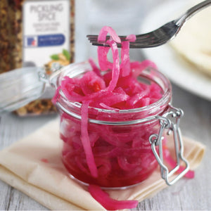 A jar of pickled red onions with a fork holding a piece of onion.