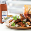 A plate of barbecued pork ribs with dragon fruit and cilantro with a jar of Private Selection Barbecue Spice in the background.