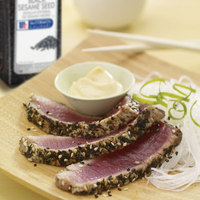 Sliced tuna with sesame seeds and a side of white noodles and a small bowl of mayonnaise.