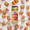 A bottle of McCormick Salted Caramel Pecan seasoning is surrounded by unwrapped and wrapped caramel candies.