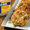 A plate of Old Bay Crab Cake Classic with a box of Old Bay seasoning in the background.