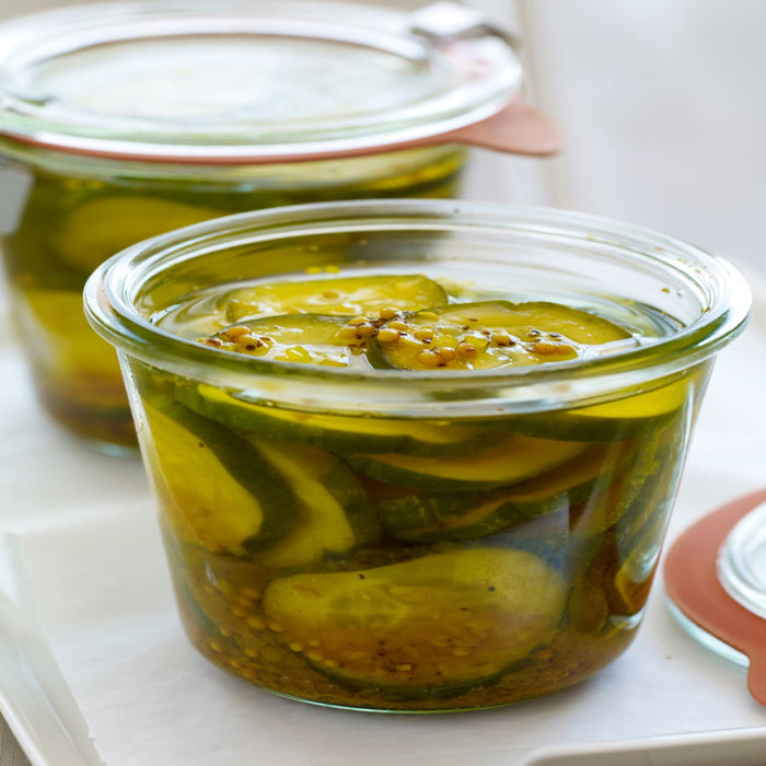 A jar of dill pickle spears with mustard seeds.