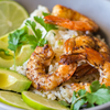 A bowl of rice with shrimp avocado and lime.
