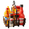 A black metal condiment caddy holds a variety of flavor enhancers including Old Bay Hot Sauce, McCormick Sea Salt Grinder, McCormick Black Peppercorn Grinder, Frank's RedHot Original Cayenne Pepper Sauce, Cholula Original Hot Sauce, and French's Mustard.