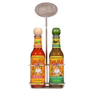A metal tabletop caddy holds two five ounce bottles of Cholula Hot Sauce in Original and Green Pepper flavors featuring the iconic wooden caps and brand logo.