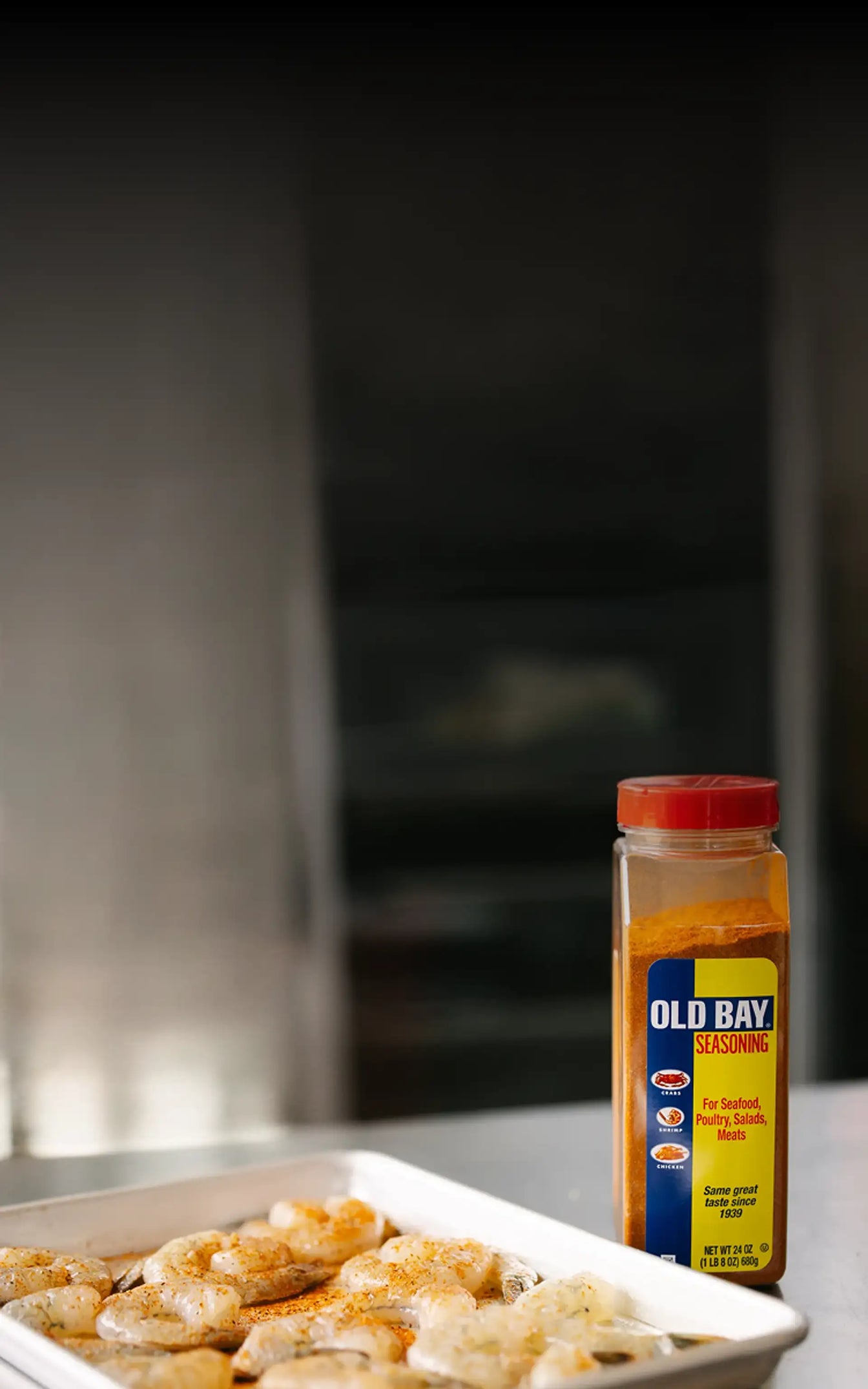 Shrimp on a plate with Old Bay seasoning bottle in the background