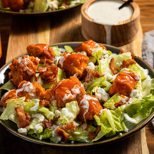 A vibrant buffalo cauliflower salad is drizzled with creamy dressing and topped with crispy bacon bits and blue cheese crumbles.