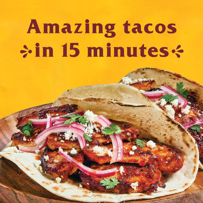 A close-up of a delicious taco with chicken red onion cilantro and cheese.