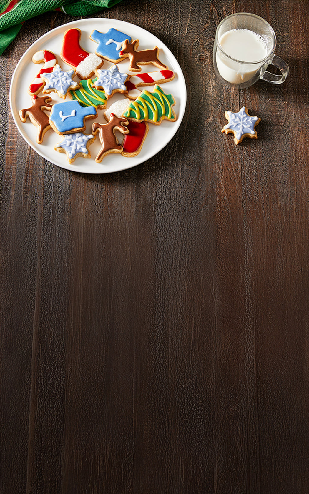 Decorative cookies on a plate with a glass of milk on a wooden surface