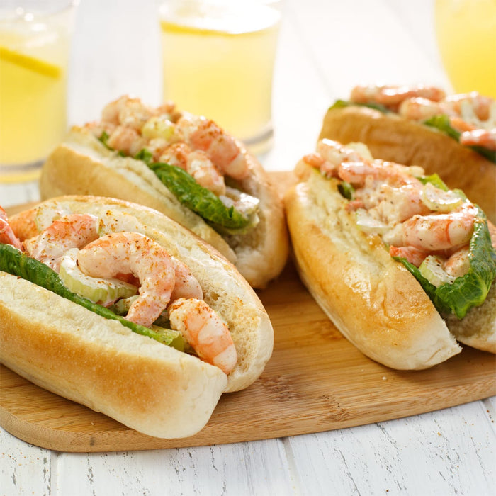 Four shrimp rolls on a wooden cutting board.