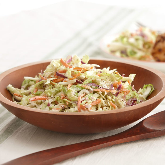 A wooden bowl filled with creamy coleslaw.