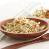 A wooden bowl filled with creamy coleslaw.