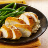 A plate of sliced chicken breast with a yellow sauce green beans and rice.