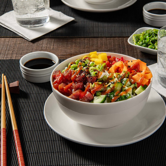 A bowl of poke with rice, tuna, cucumber, carrots, and other toppings.