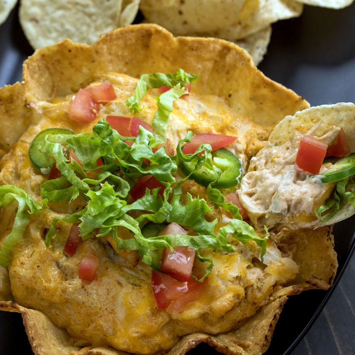 A close-up of a taco shell filled with chicken, cheese, lettuce, tomatoes, and jalapenos.