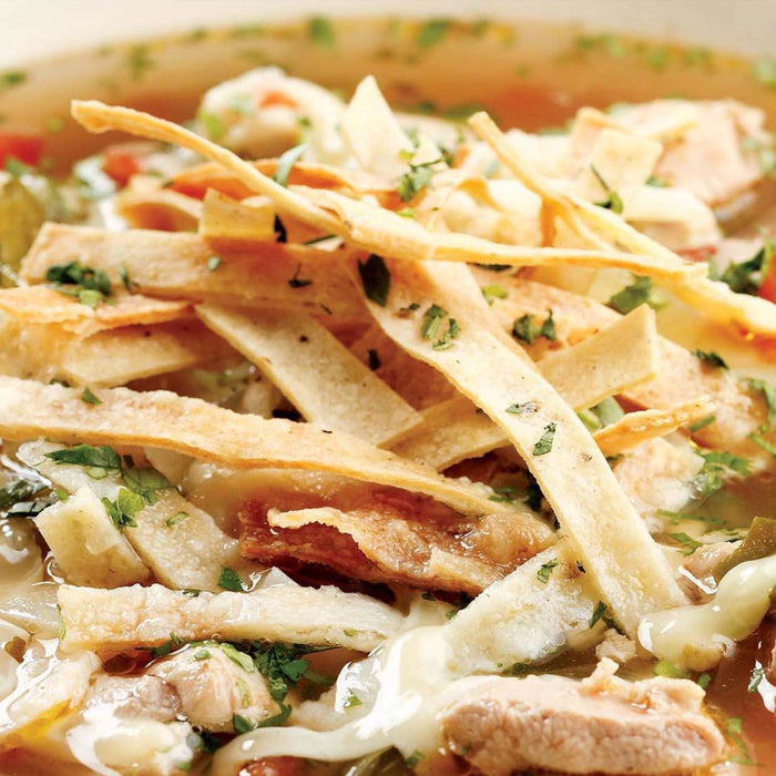 A close-up of a hearty chicken tortilla soup, topped with crispy tortilla strips, fresh cilantro, and tender chicken, a dish often seasoned with Mccormick Ground Cumin Mcp.
