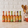 A row of seven different flavored Cholula hot sauces.