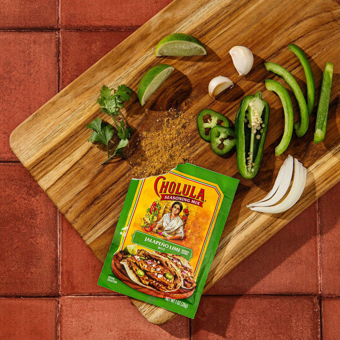 A packet of Cholula Jalapeno Lime Hot Seasoning Mix with ingredients on a wooden cutting board.