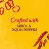 A graphic illustration for Cholula Hot Sauce featuring sliced and dried peppers on a yellow background with text stating it is crafted with arbol and piquin peppers.