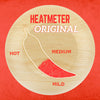 A wooden circle with a red chili pepper graphic and the words Heatmeter Original on it.