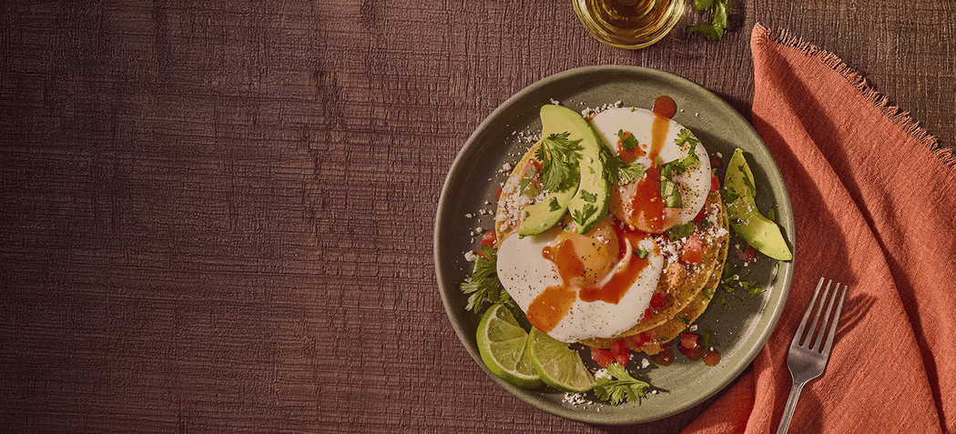Plated dish with avocado, lime, and sauce on a wooden table