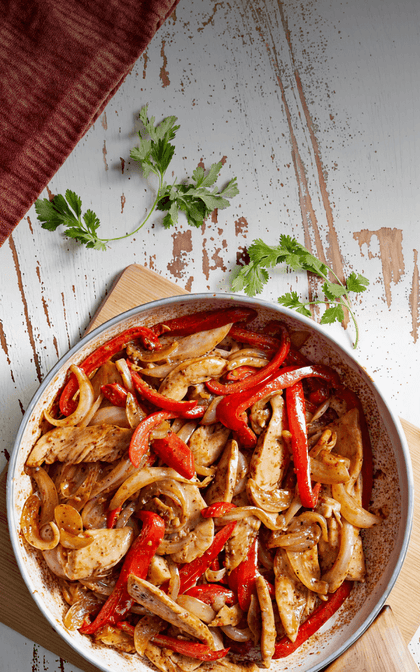 Skillet with chicken fajitas on a rustic wooden surface