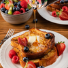 A plate of french toast topped with fresh fruit and a drizzle of maple syrup.