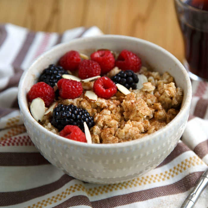 A bowl of oatmeal topped with raspberries, blackberries, and almonds.