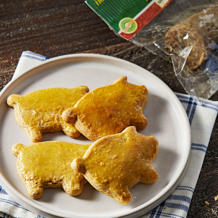 Four gingerbread cookies shaped like pigs are on a white plate.