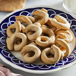 A plate of freshly baked, golden brown, ring-shaped cookies.