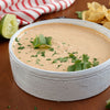 A white bowl filled with a creamy dip topped with cilantro.