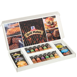 An open white gift box displays a variety of McCormick Grill Mates seasonings and marinades, with the inside lid featuring a collage of grilled foods.