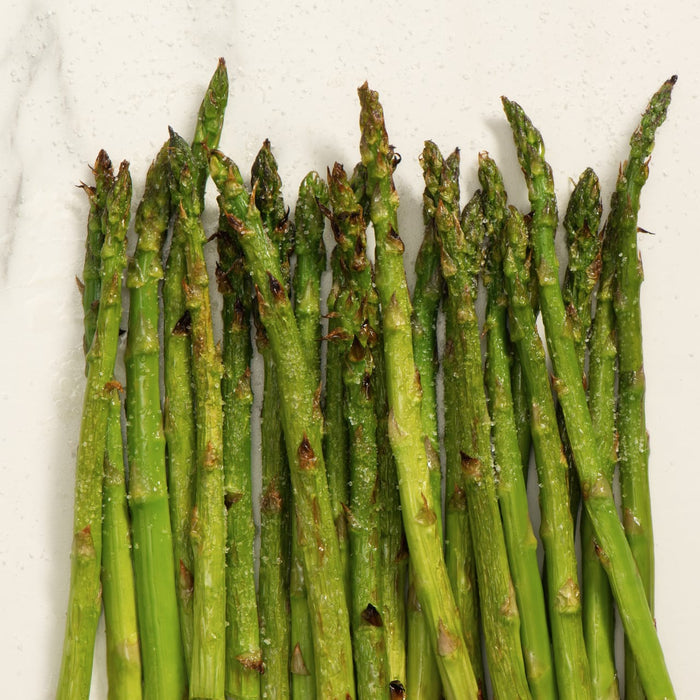 A bunch of asparagus spears are arranged in a row, with the tips facing up.