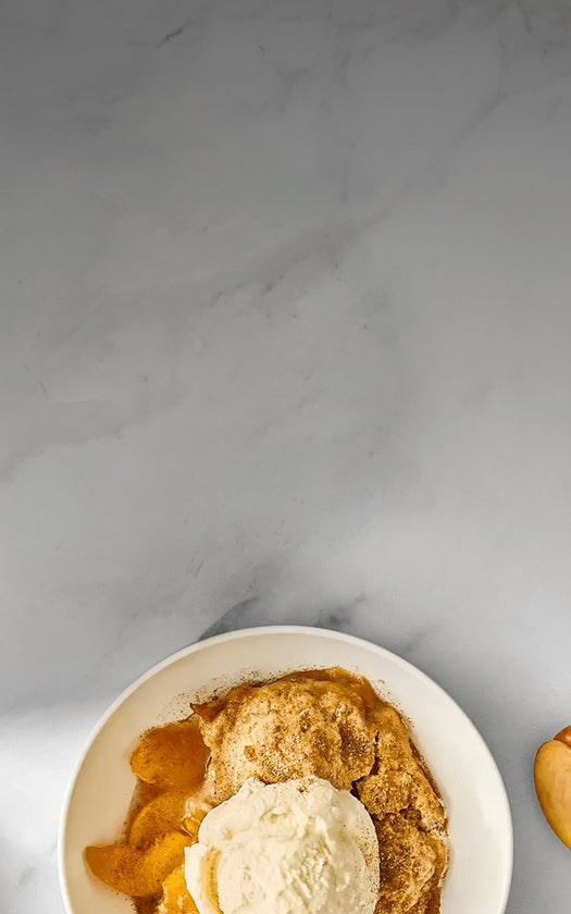 Peach cobbler with ice cream on a marble surface