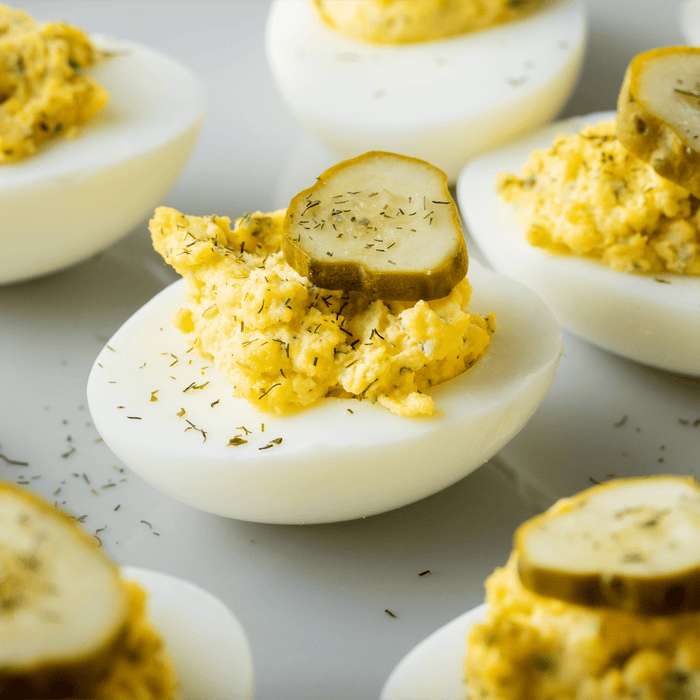Deviled eggs topped with dill and a pickle slice.
