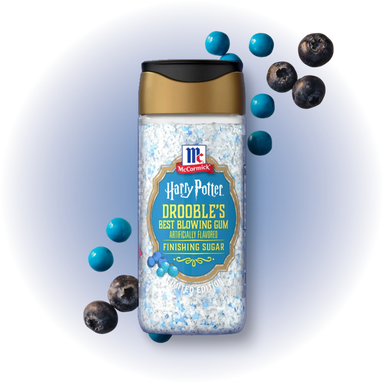A bottle of McCormick Harry Potter Drooble's Best Blowing Gum finishing sugar, styled with blue gummy candies and blueberries on a white background with a soft blue glow.