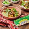 A bowl of El Guapo Chile Serrano Molido Ground Serrano Chili with rice, lime wedges, and jalapenos.